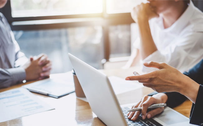 テーブルに座りノートパソコンを使ってミーティングしている様子