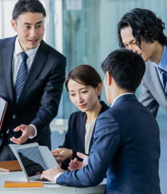 ビジネスの会議中、数人がノートパソコンを注視している画像